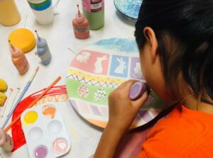 Girl painting an Easter pottery plate in ceramics class
